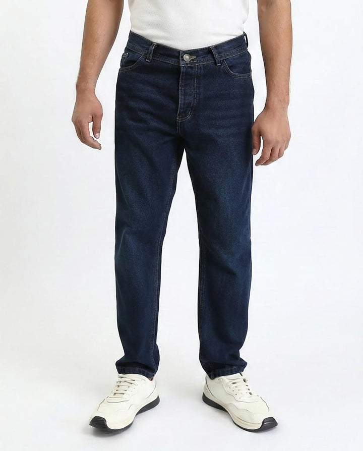 Person wearing dark blue jeans and white sneakers on a white background