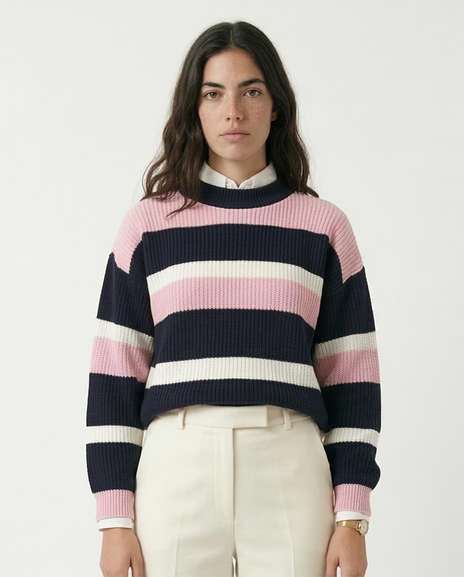 Person wearing a striped sweater with navy, pink, and white colors on a plain background