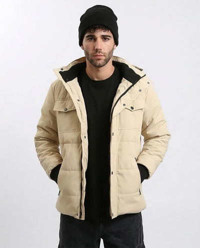 Man wearing a beige quilted jacket with black accents on a white background