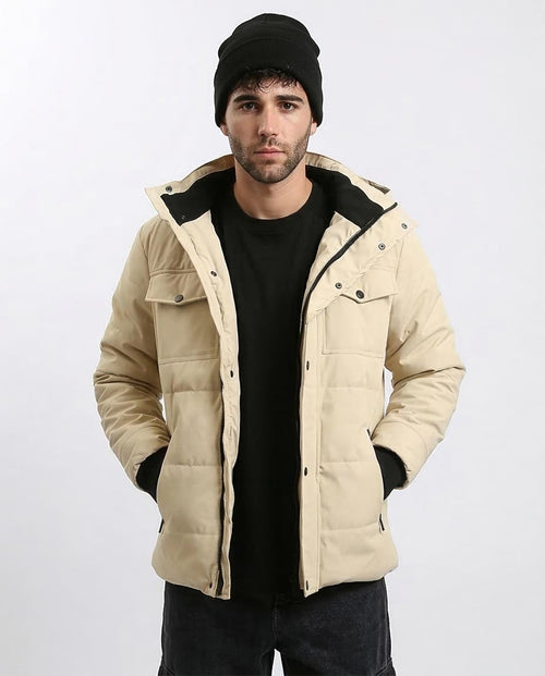 Man wearing a beige quilted jacket with black accents on a white background