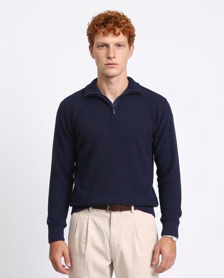 Man wearing a navy blue sweater with a zipper on a light gray background