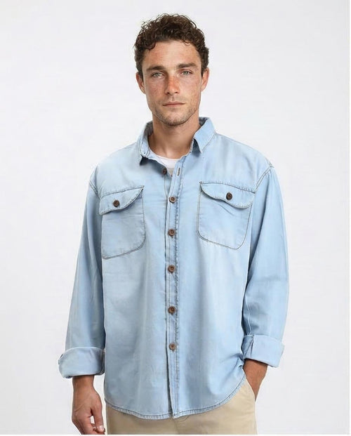 Man wearing a light blue denim shirt on a plain background