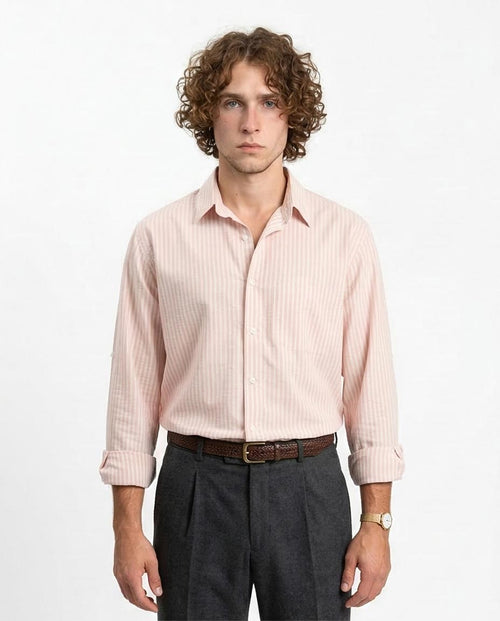 Man wearing a light pink striped shirt and dark gray pants on a white background