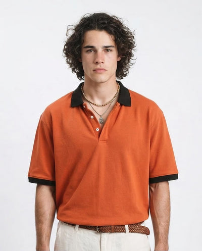 Man wearing an orange polo shirt with black trim on a white background