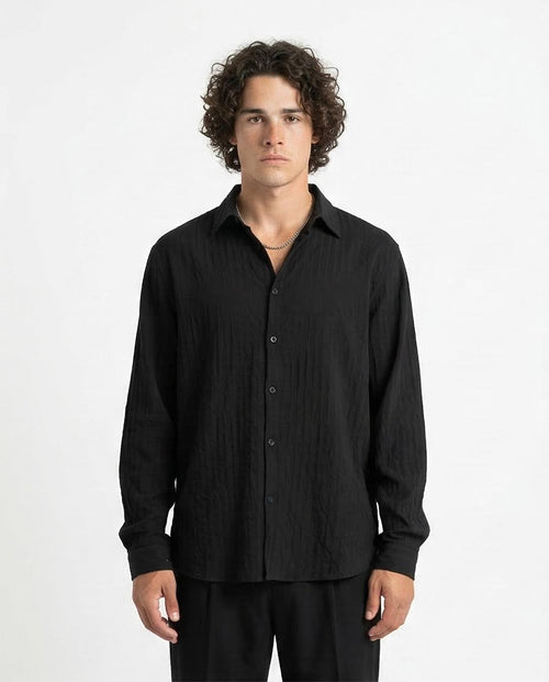 Man wearing a black button-up shirt against a white background