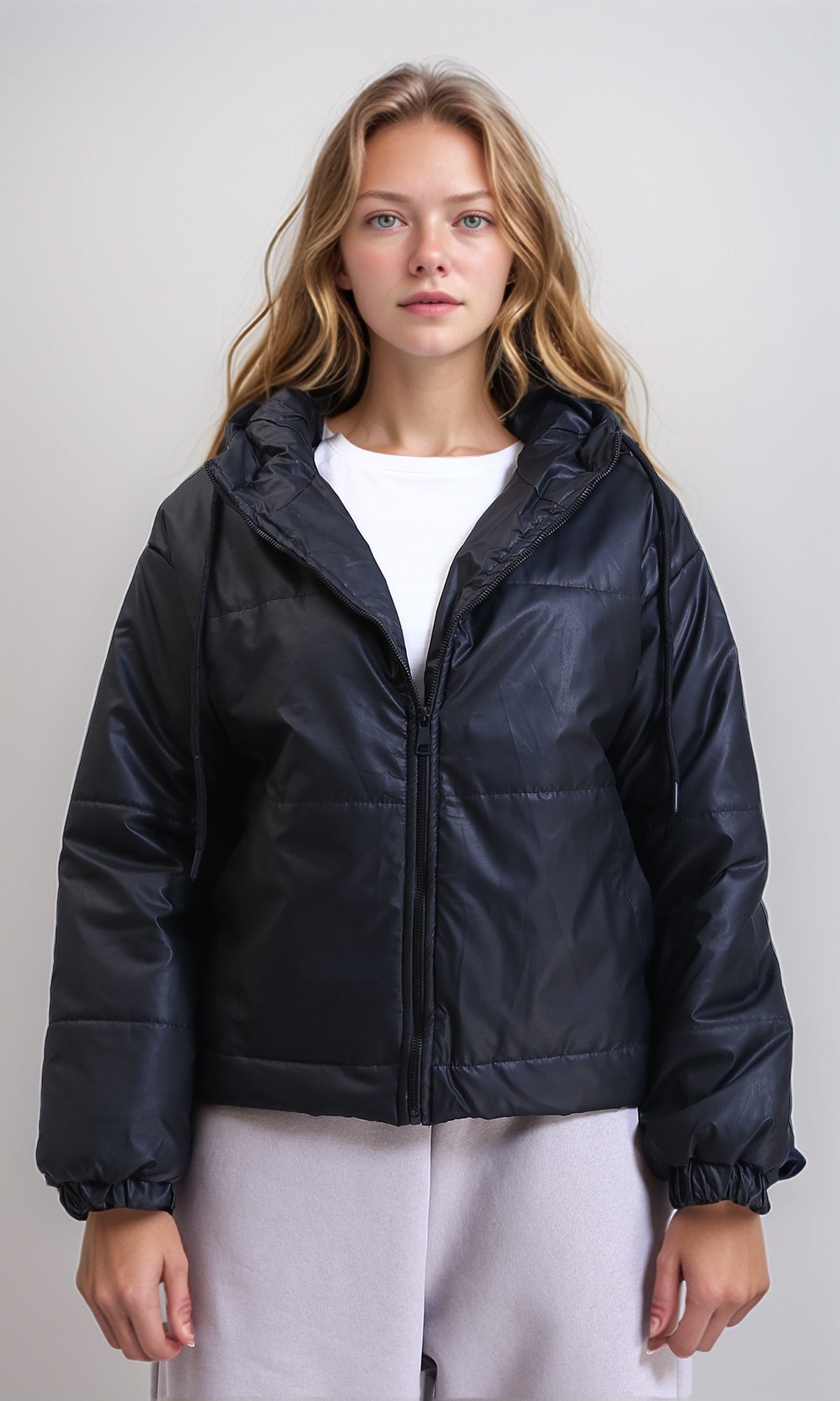 Woman wearing a black puffer jacket over a white shirt on a plain background