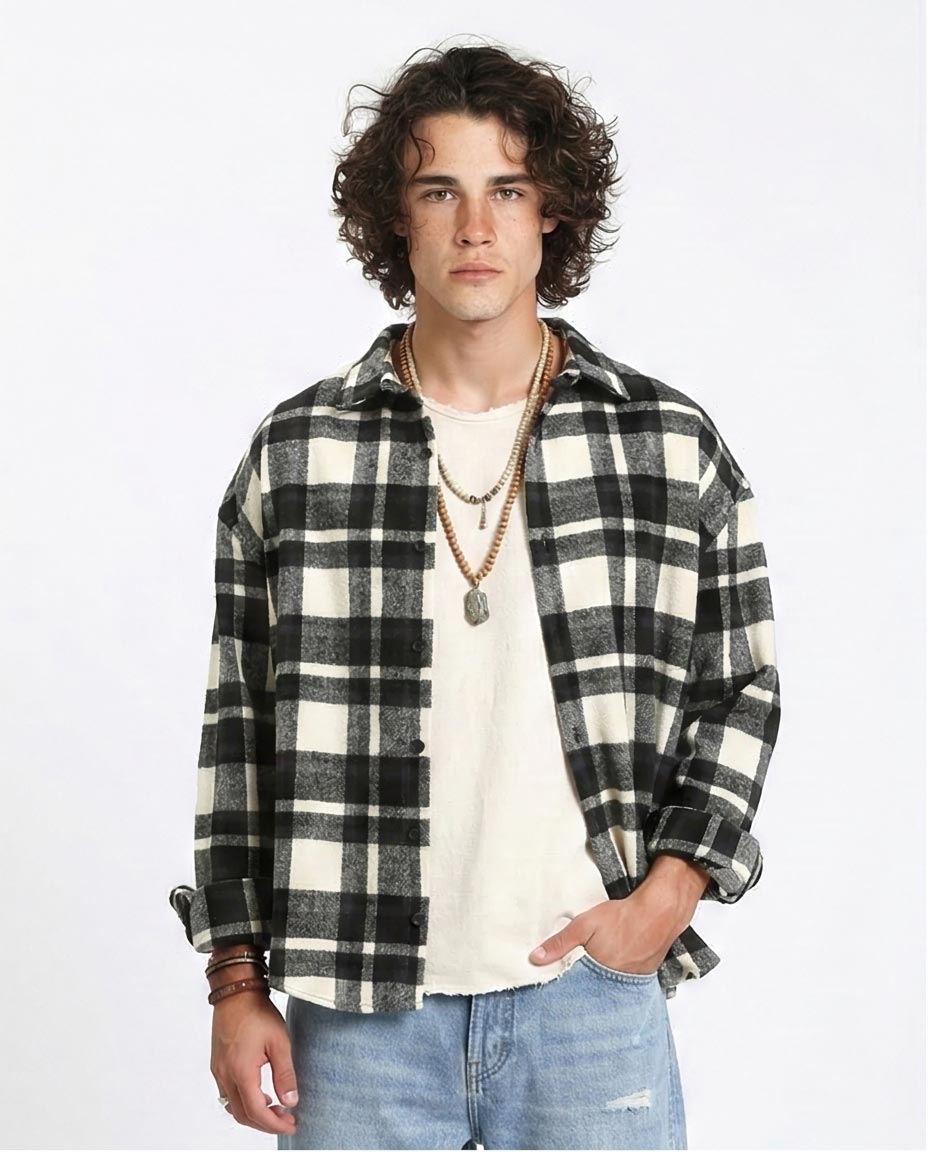 Man wearing a black and white checkered shirt over a white t-shirt with a plain background