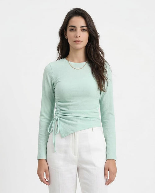 Woman wearing a light green long-sleeve top with a tie detail on a white background