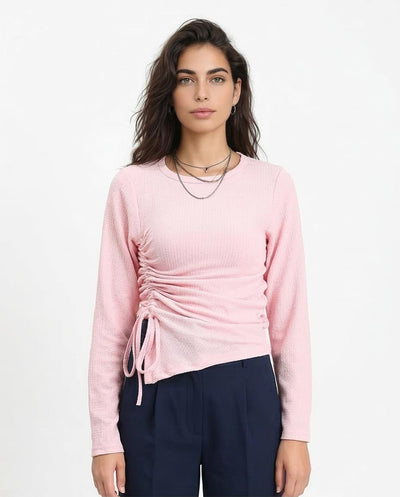 Woman wearing a pink long-sleeve top with a tie detail on a white background