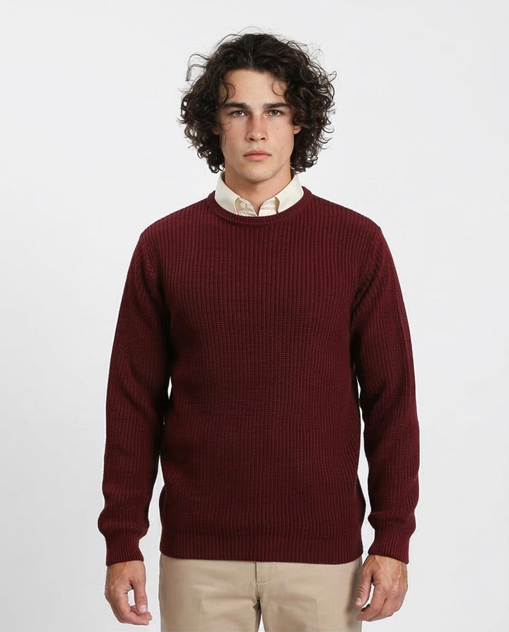 Man wearing a burgundy sweater over a white shirt on a plain background