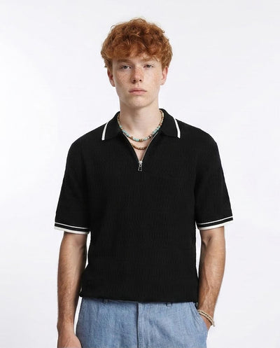 Man wearing a black polo shirt with white trim on a white background