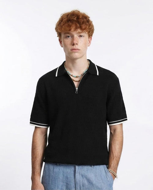 Man wearing a black polo shirt with white trim on a white background