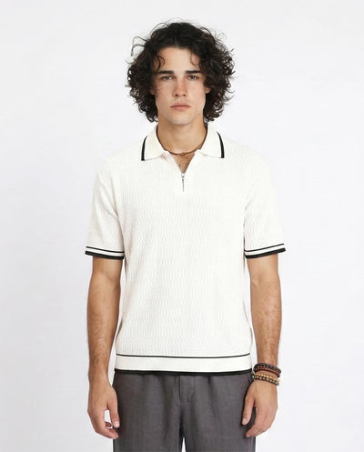 Man wearing a white polo shirt with black trim on a plain background