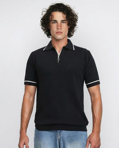 Man wearing a black polo shirt with white trim on a plain background