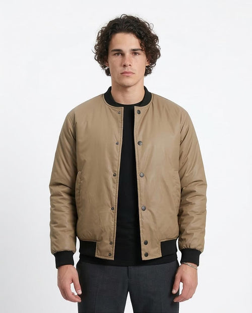 Man wearing a beige bomber jacket with black accents on a white background