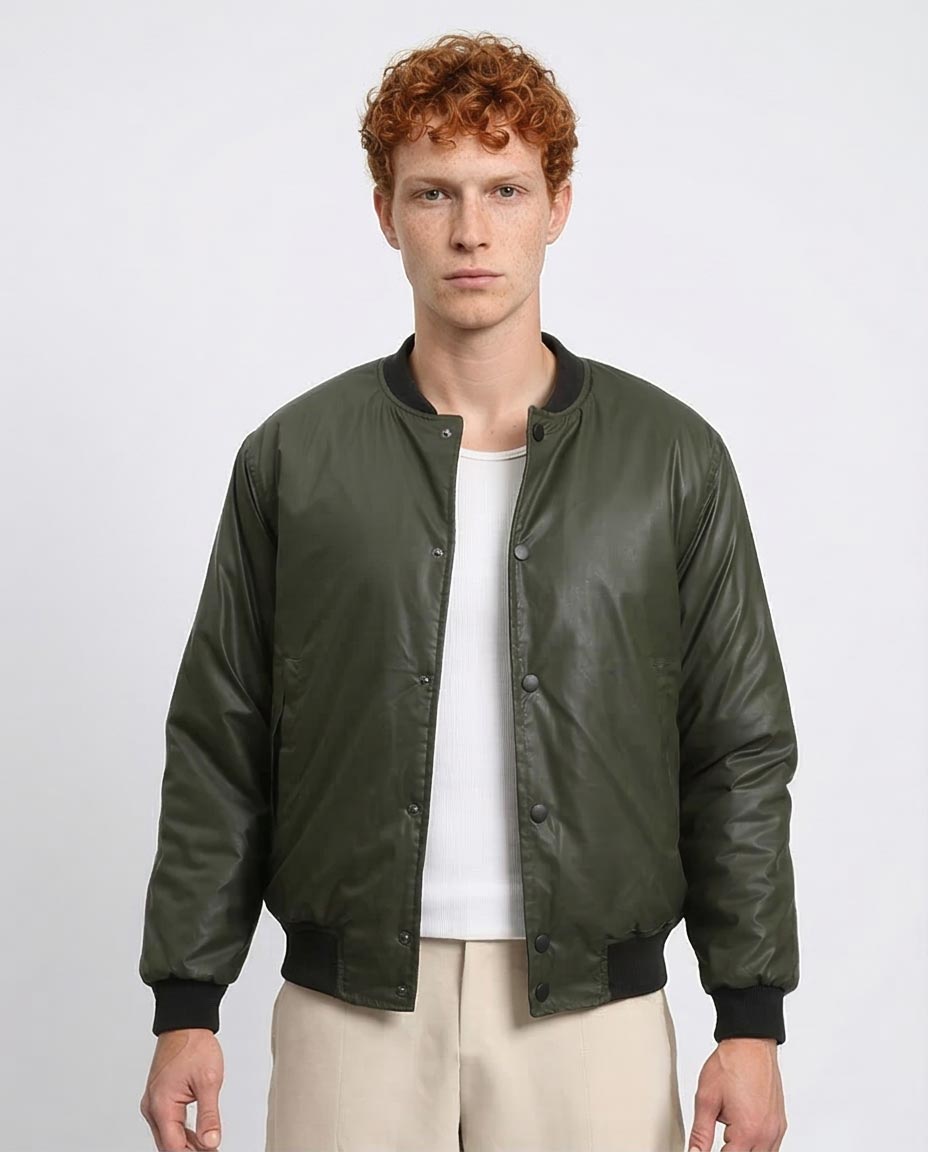 Man wearing a green bomber jacket over a white shirt on a light gray background