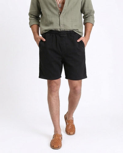 Man wearing a green shirt and black shorts on a white background