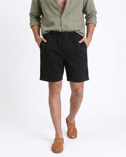 Man wearing a green shirt and black shorts on a white background