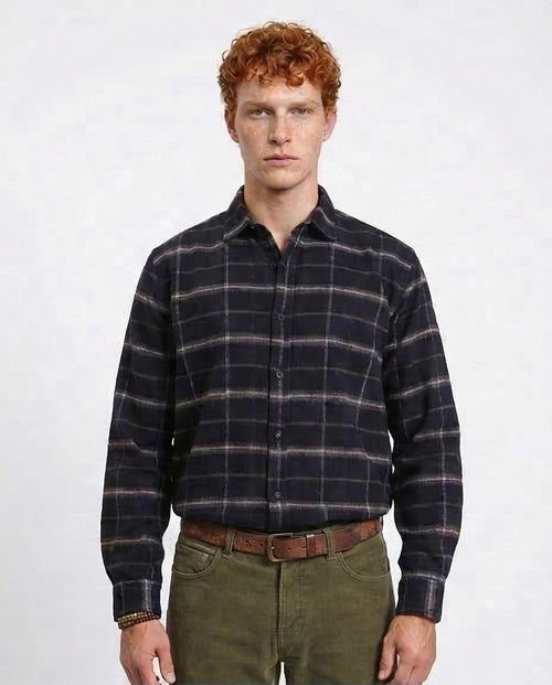 Man wearing a plaid shirt and green pants on a white background