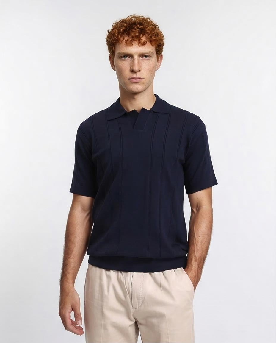 Man wearing a navy blue polo shirt and beige pants on a white background