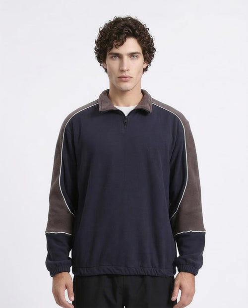 Man wearing a navy and brown long-sleeve shirt with a white background