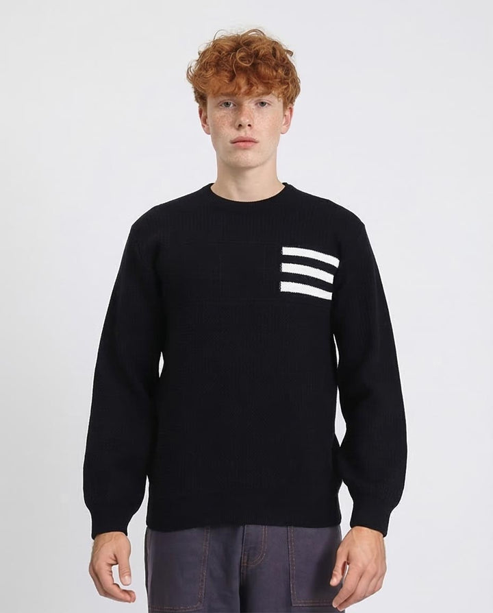 Person wearing a black sweater with white stripes on a plain background