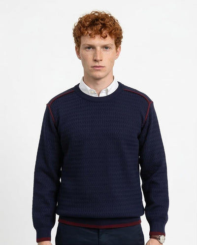 Man wearing a navy sweater with red accents on a white background