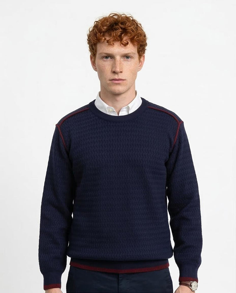 Man wearing a navy sweater with red accents on a white background