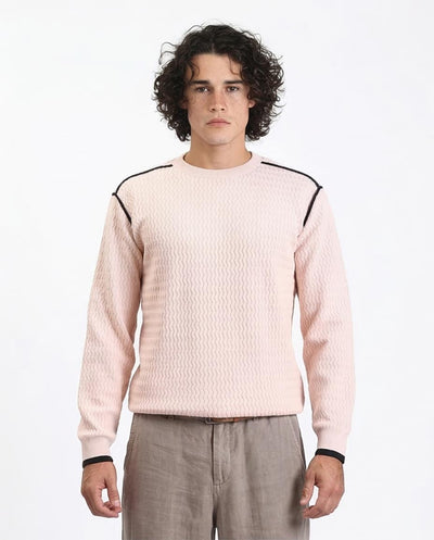 Man wearing a light pink sweater with black accents on a white background