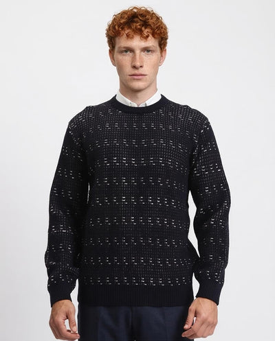 Man wearing a dark patterned sweater on a light gray background