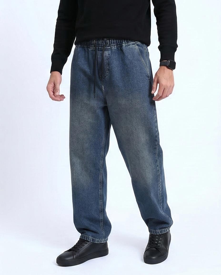 Person wearing blue jeans and black shoes on a white background