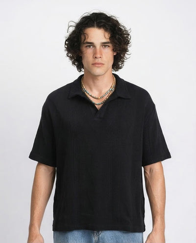 Man wearing a black polo shirt against a plain background