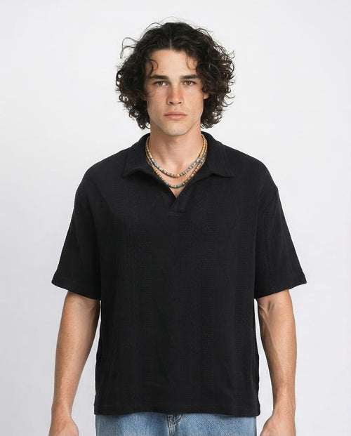 Man wearing a black polo shirt against a plain background