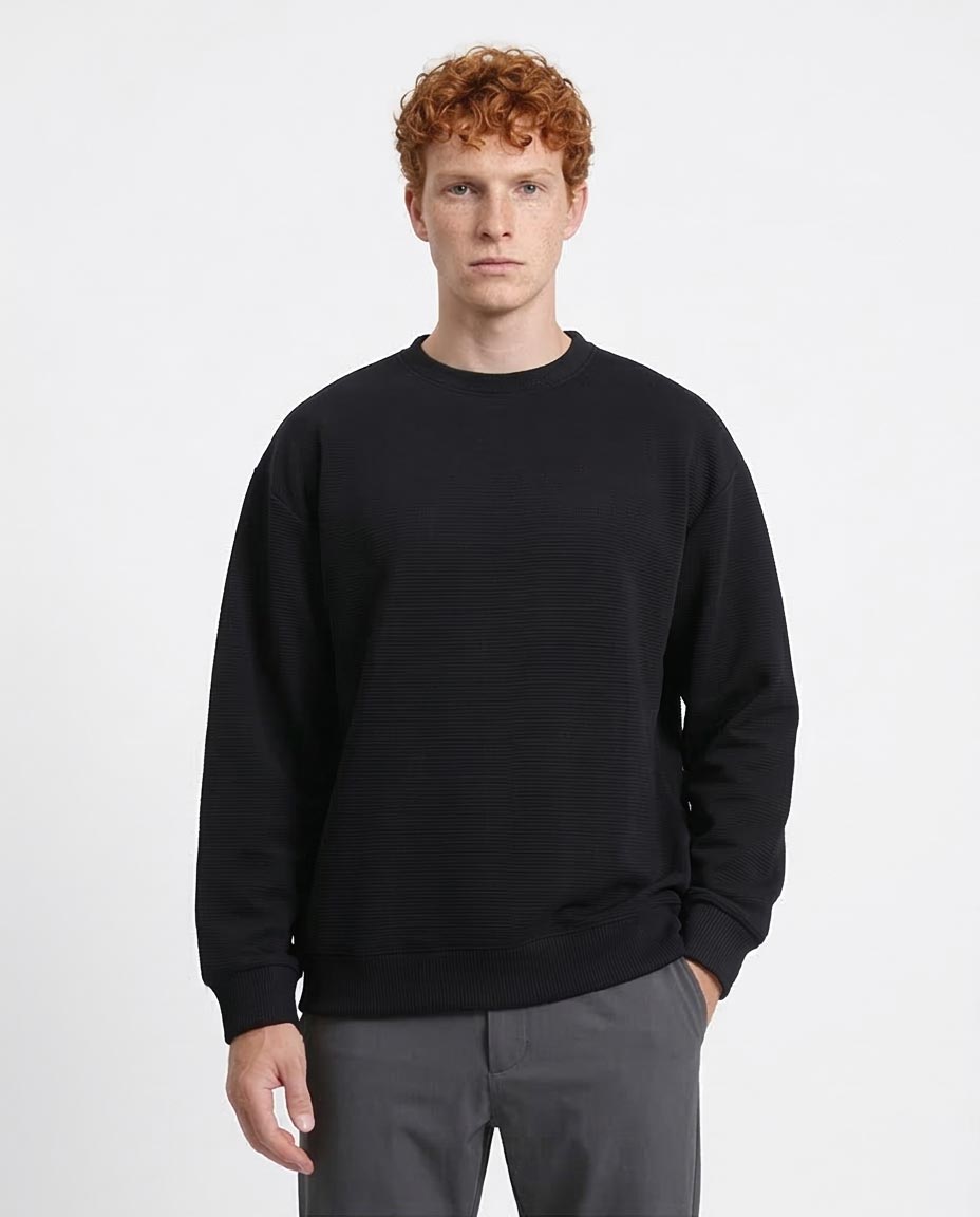 Man wearing a black sweatshirt and gray pants on a white background