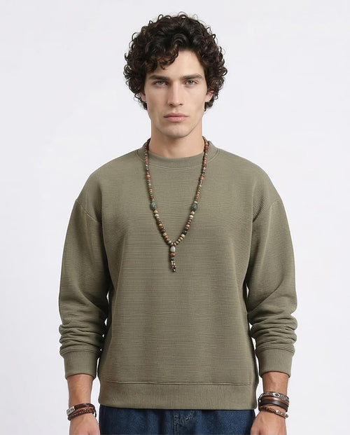 Man wearing a green sweater with a plain background