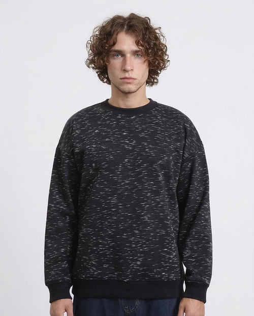 Man wearing a black patterned sweatshirt against a white background