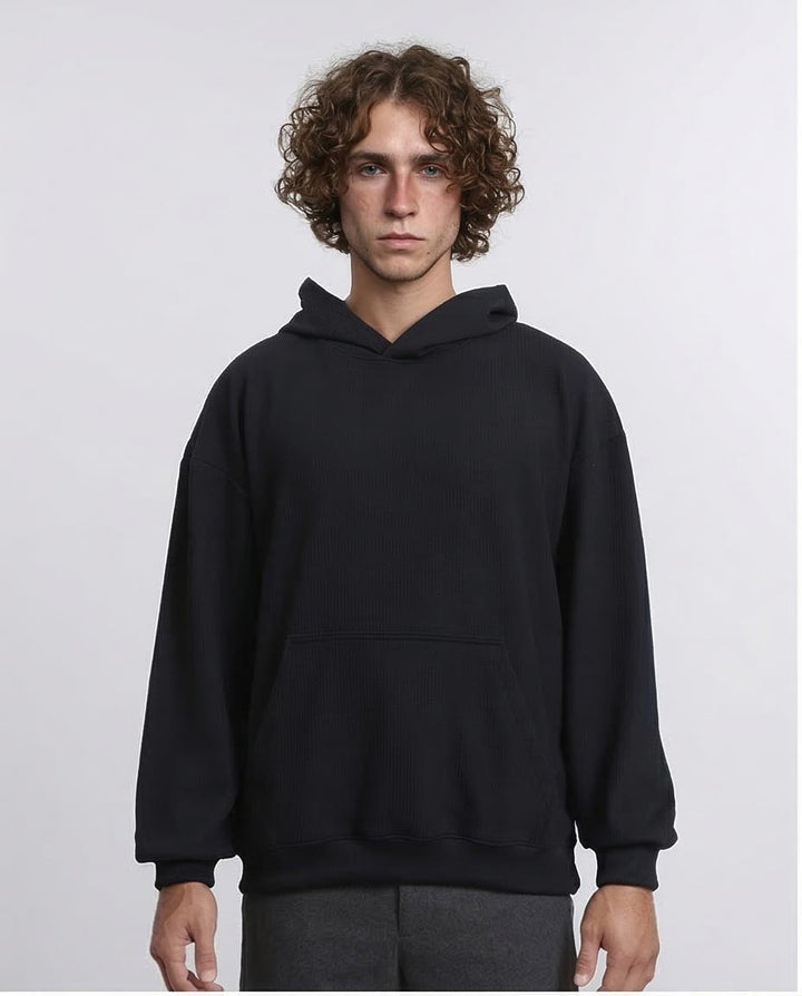 Person wearing a black hoodie against a plain background
