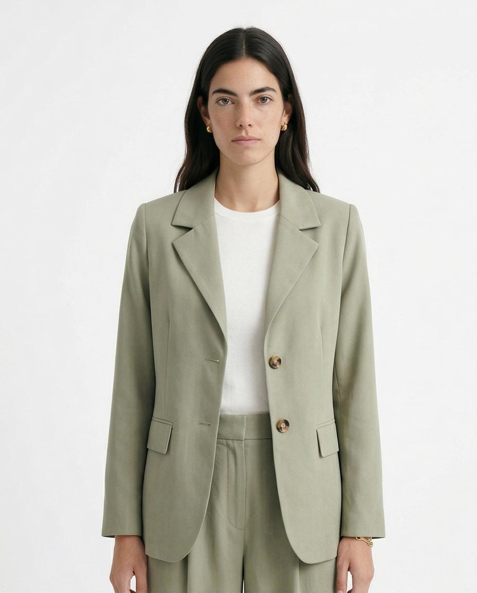 Woman wearing a light green blazer and pants on a white background