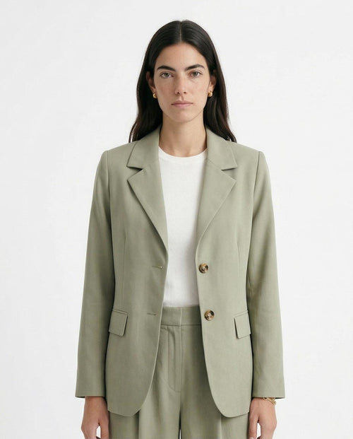 Woman wearing a light green blazer and pants on a white background