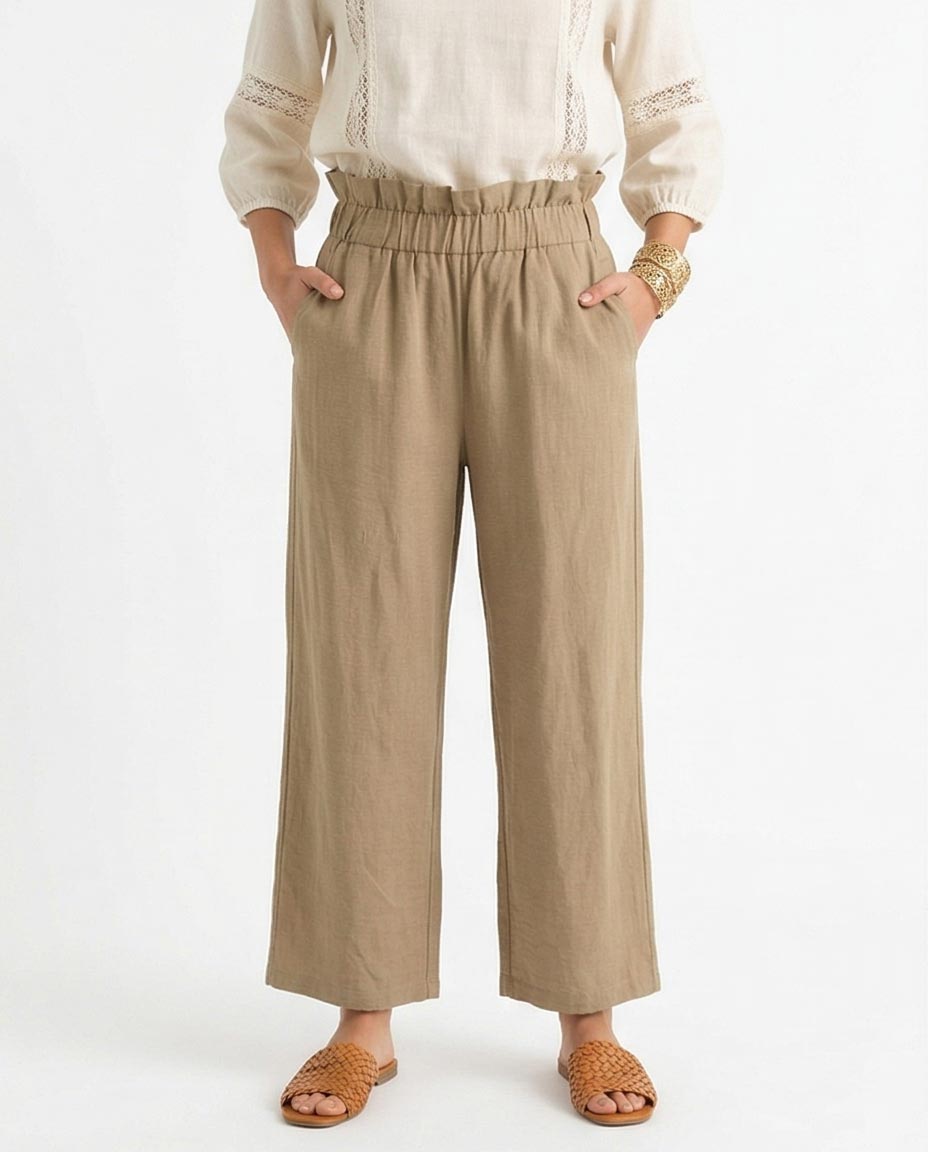 Person wearing beige wide-leg pants and a white top on a white background