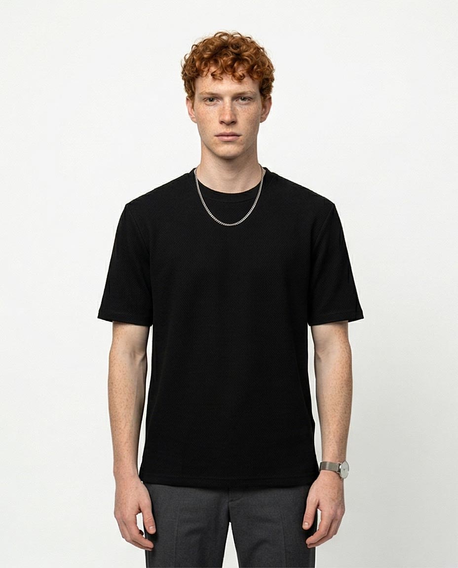 Man wearing a black t-shirt and dark pants on a white background